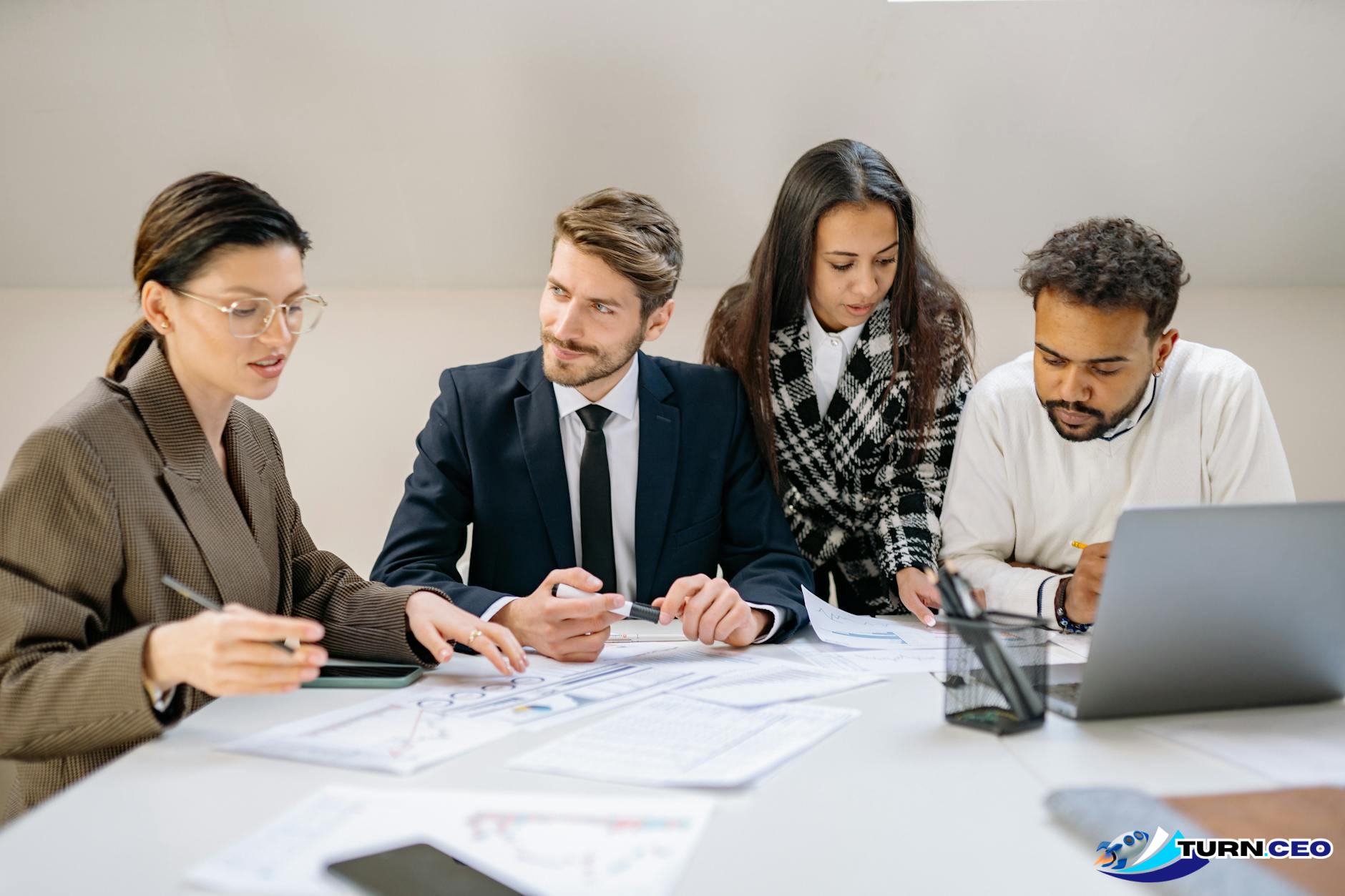 Business team collaborating with laptops and documents on conference table
