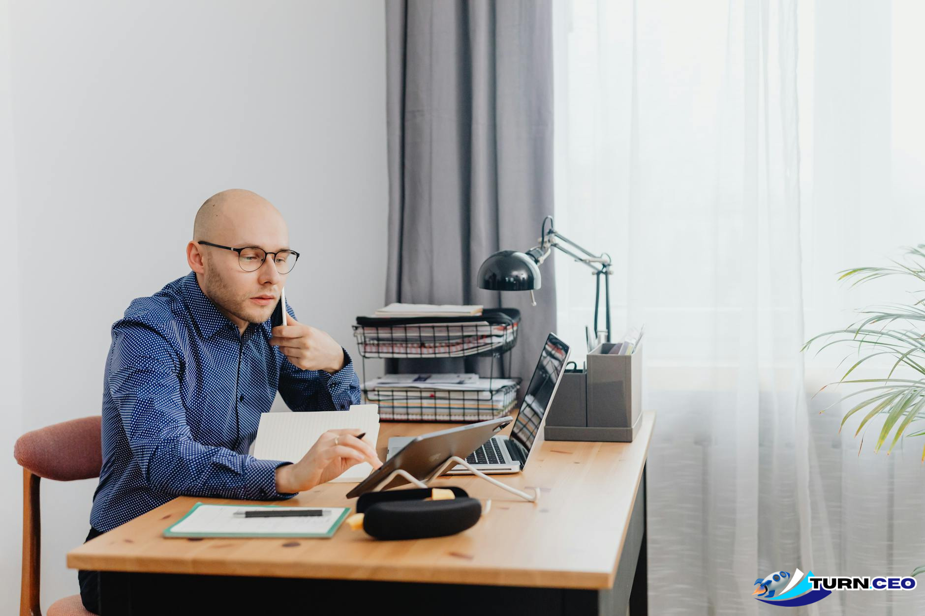 entrepreneur working on laptop with business documents scattered around desk