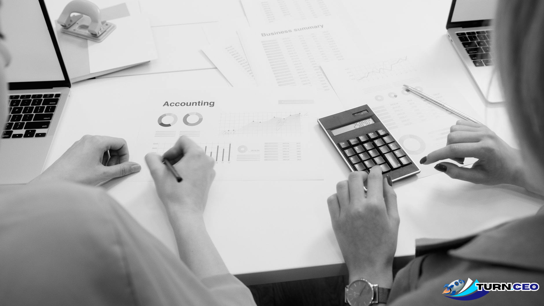 business owner reviewing financial reports on laptop with calculator and documents